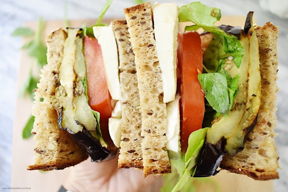 two halfs of a grilled eggplant caprese sandwich in one hand