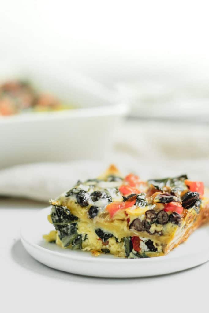 slice of casserole on small white plate with baking dish in background